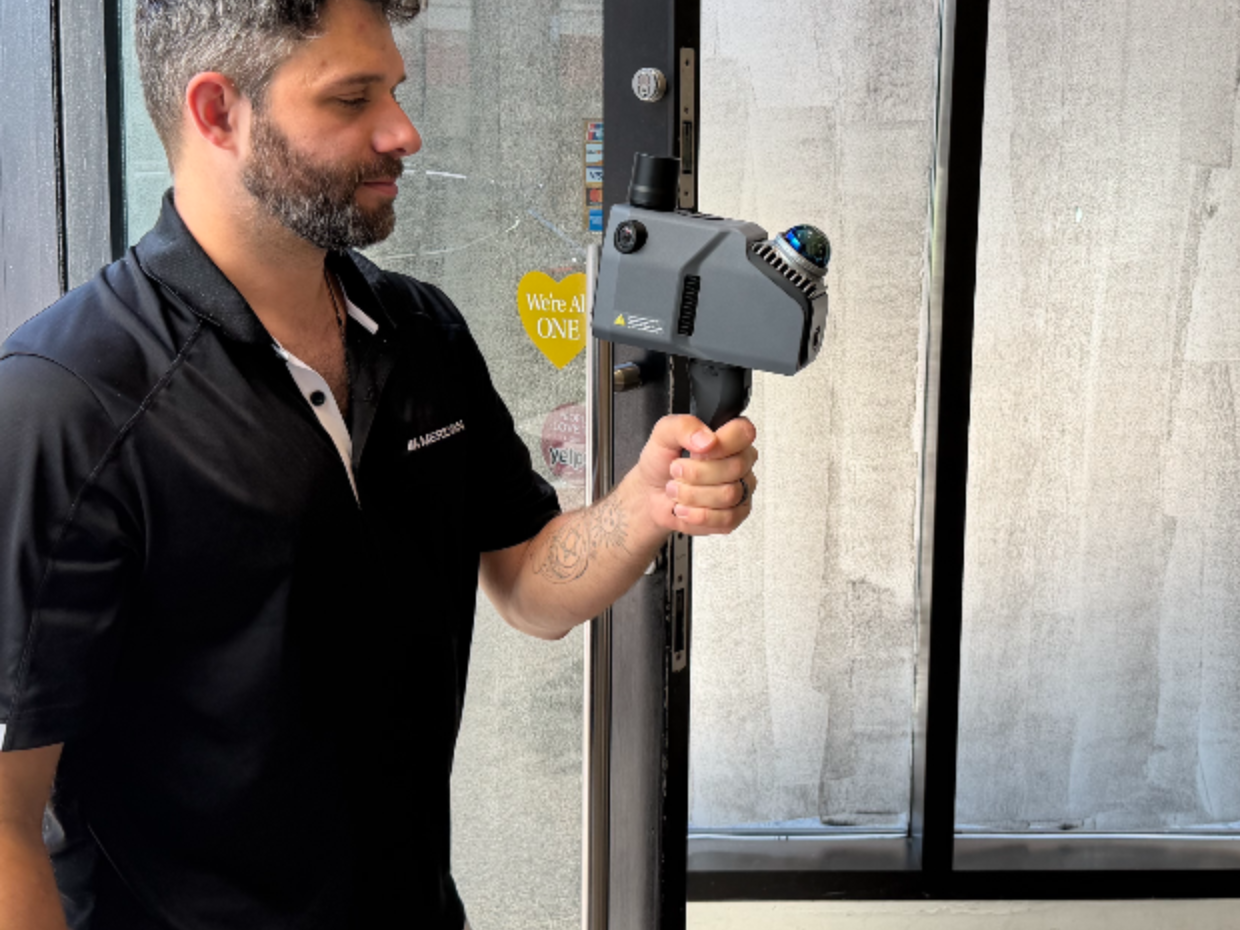 A Meridian operator scanning a storefront with a handheld sensor